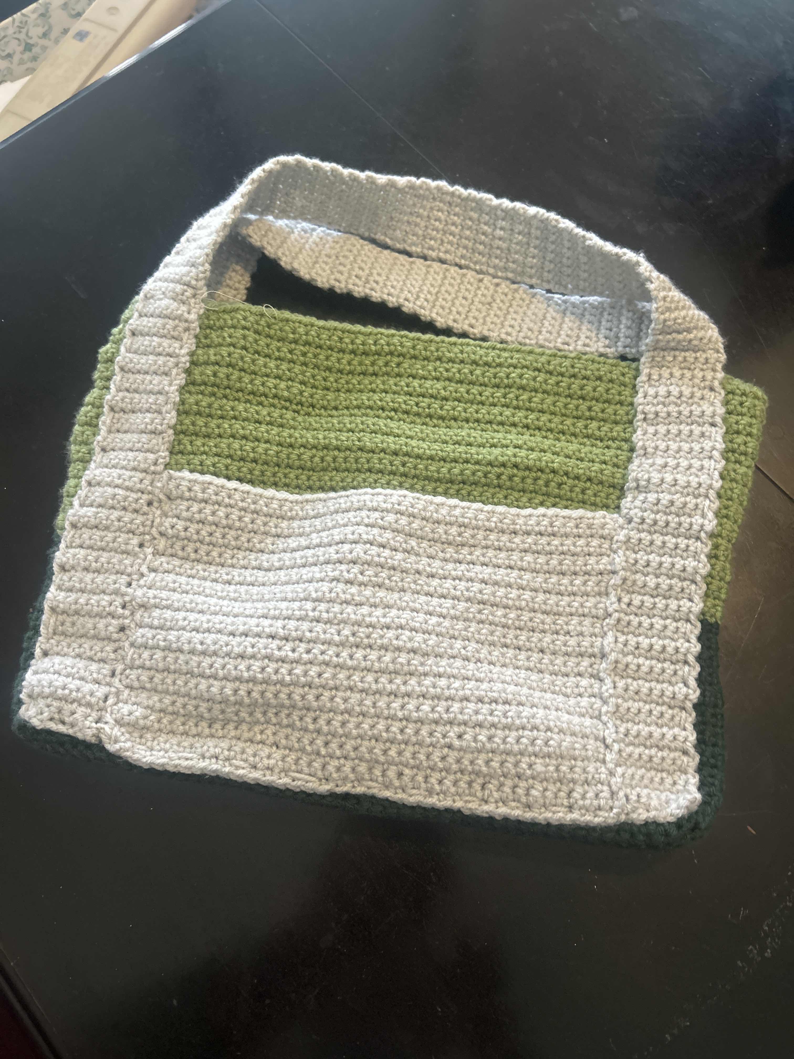 Green and grey crochet bag lying flat on surface