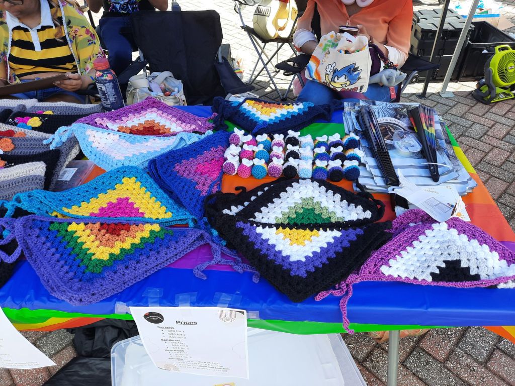 Array of pride flag bandanas and pride bees